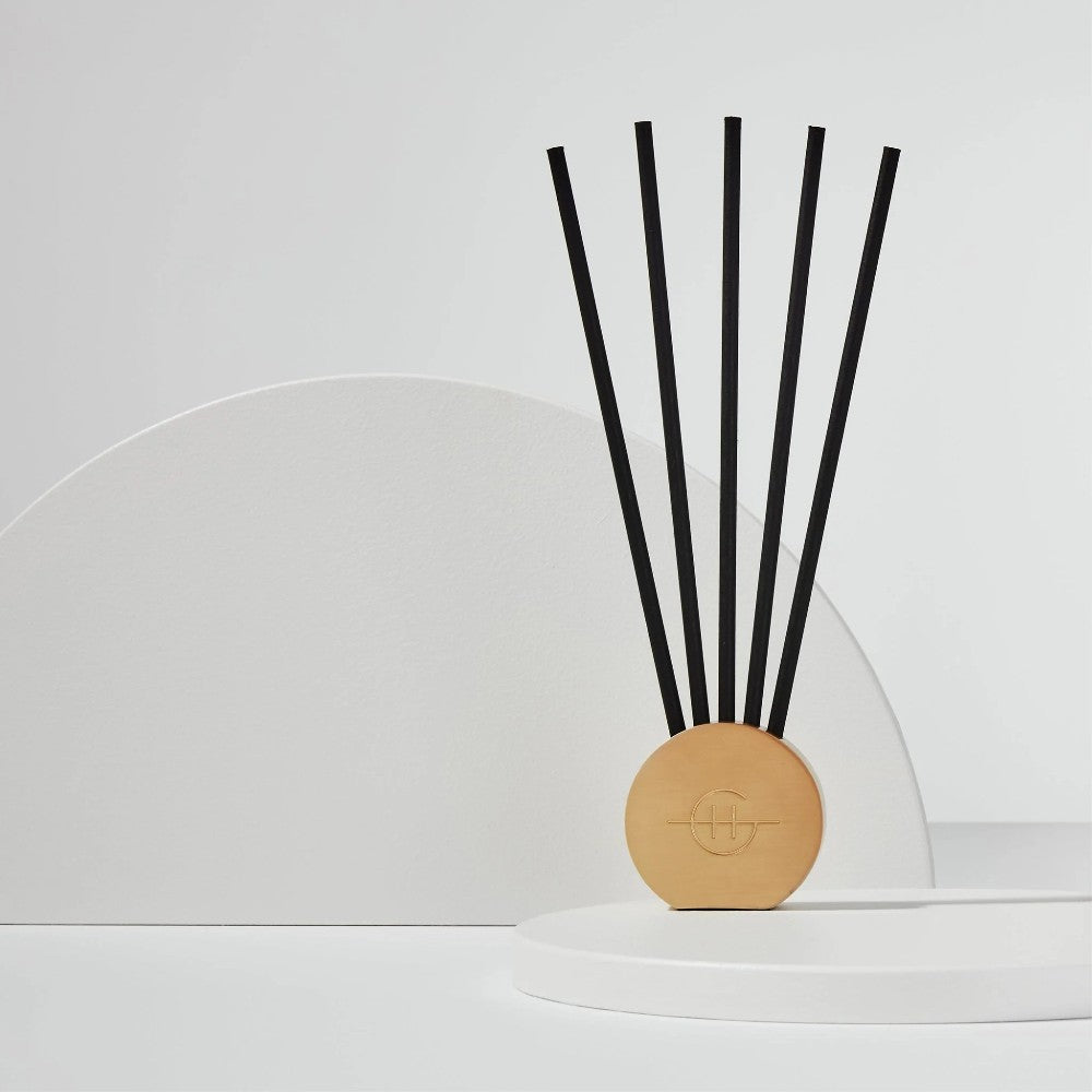 Minimalist reed diffuser with geometric backdrop.