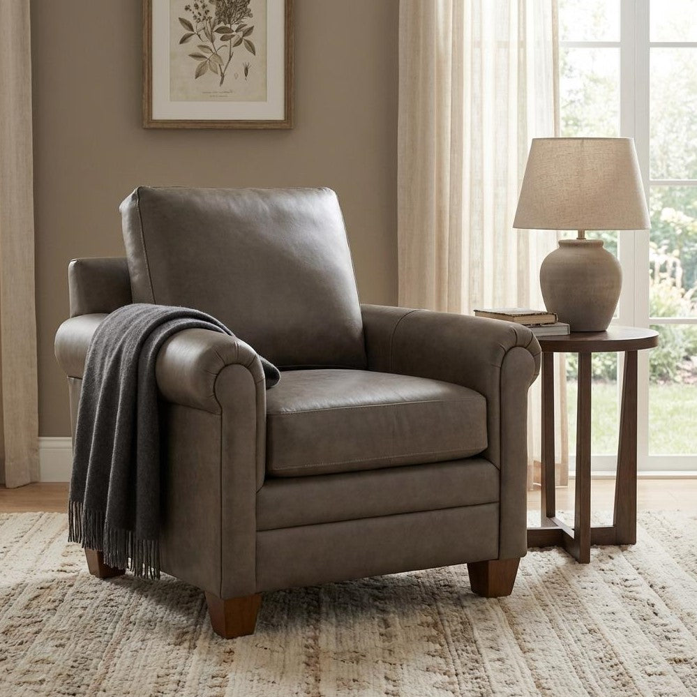 Cozy armchair with a throw, beside a lamp and table, in a sunlit room.