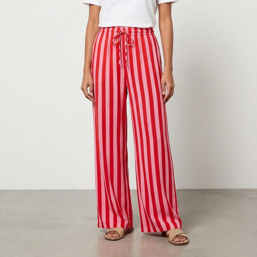 Woman in red-striped pants and white top stands indoors.