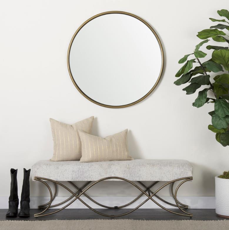 Modern entryway with bench, round mirror, boots, and a plant.
