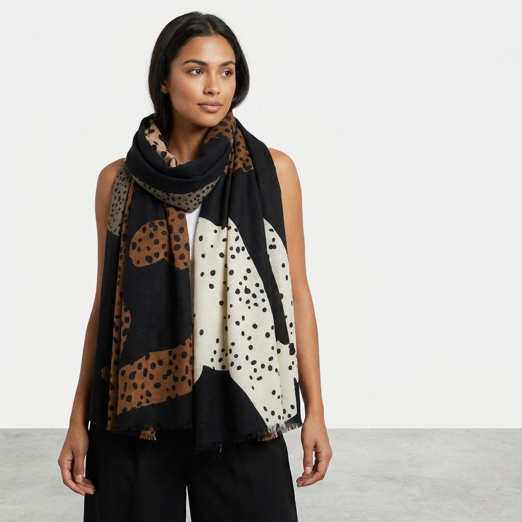 Woman wearing a patterned scarf with black, brown, and cream colors.