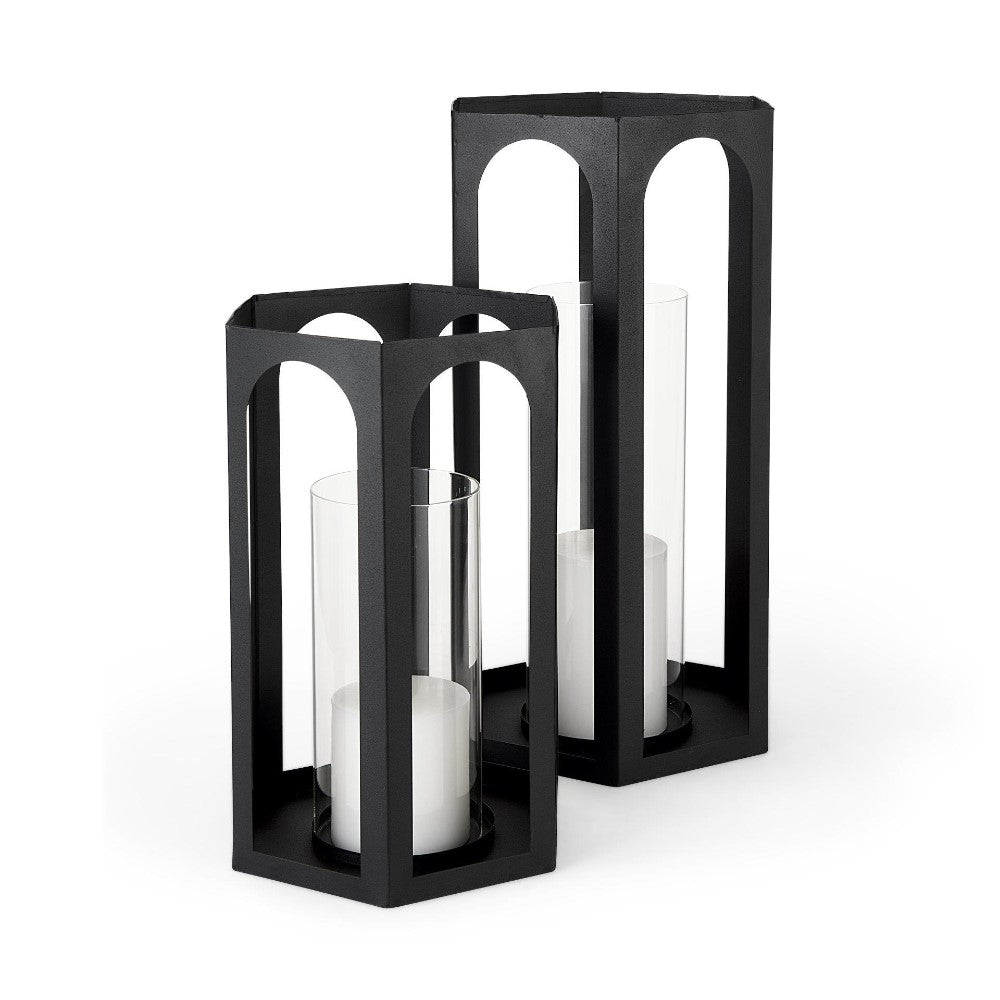Two black metal lanterns with glass cylinders and white candles inside.