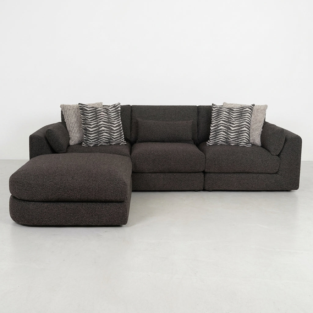 Dark L-shaped sofa with patterned cushions on a light floor.