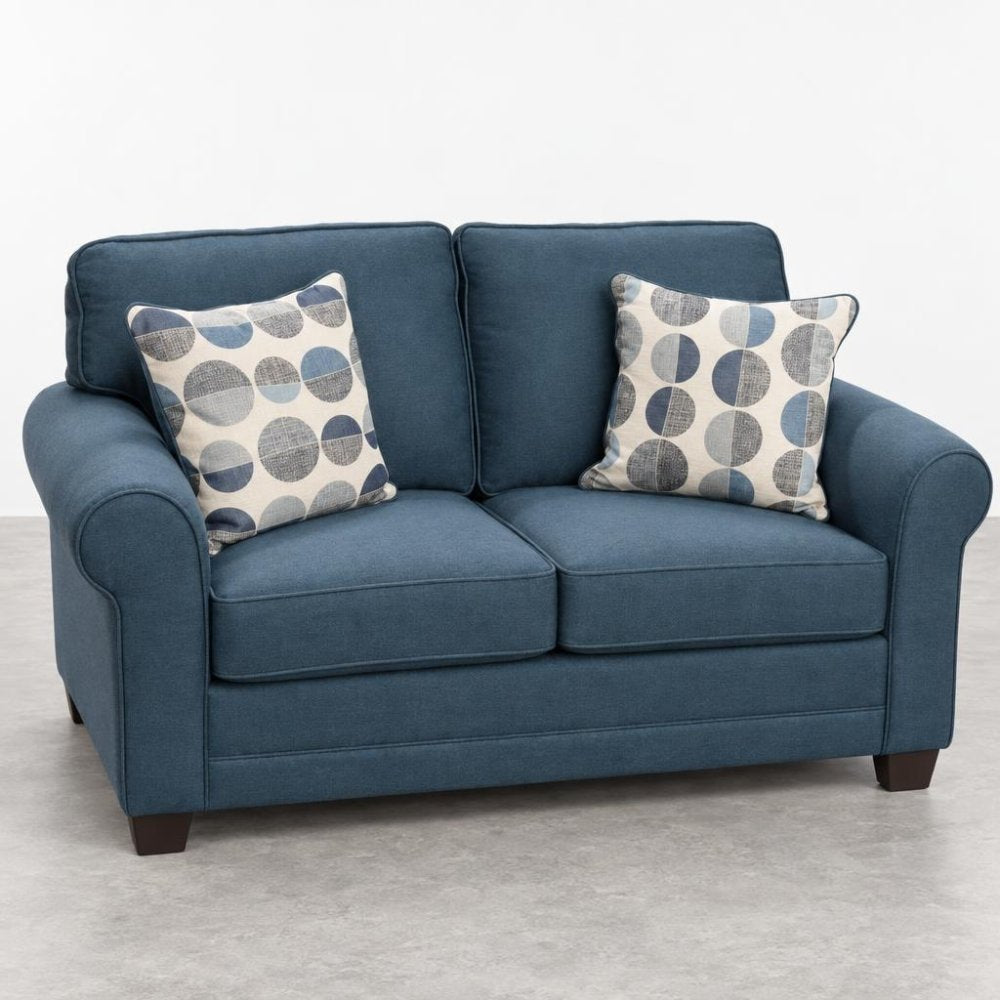 Blue loveseat with circle-patterned pillows on a gray floor.