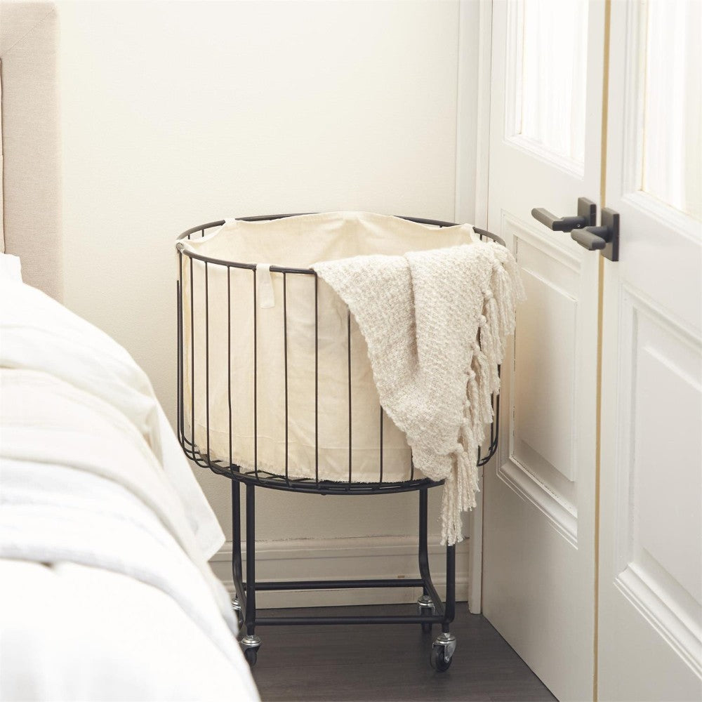 Wire laundry basket with beige fabric and a textured blanket.