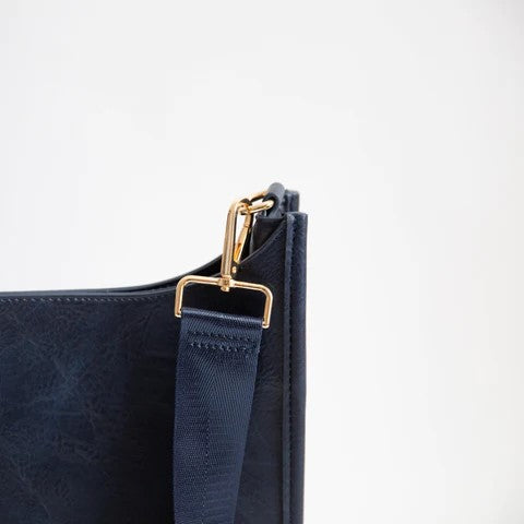 Blue bag corner with gold clasp and navy strap on white background.