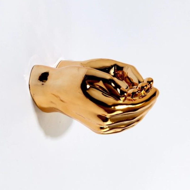 Golden hand sculpture cupping delicate objects.