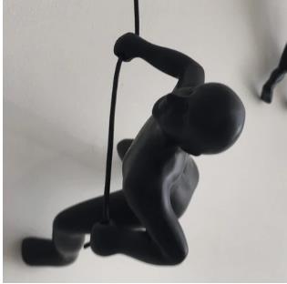 Sculpted figure climbing a rope, mounted on a wall.