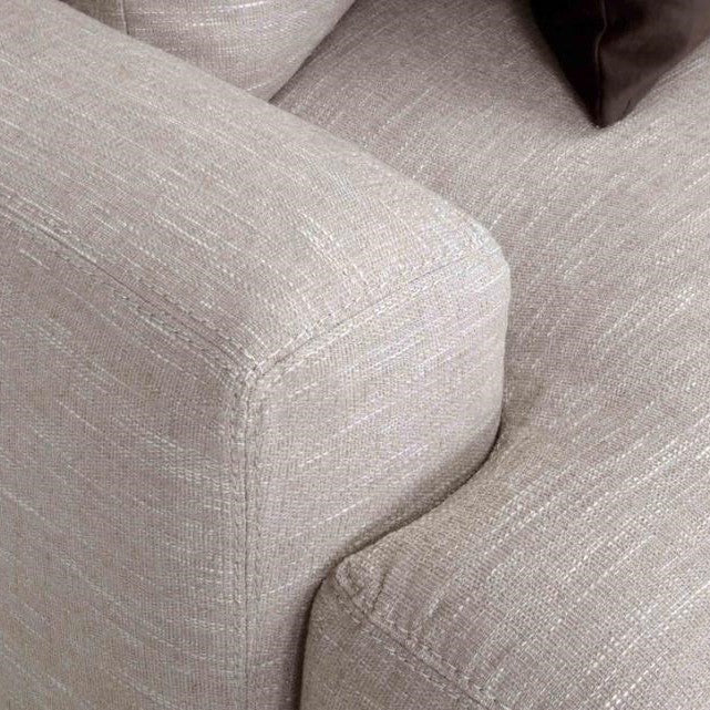 Beige upholstered sofa corner with dark cushion.