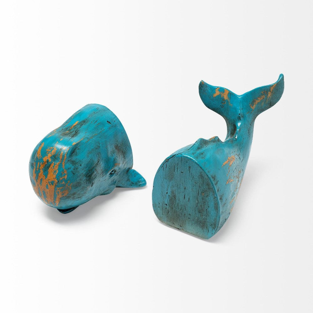 Two distressed turquoise whale bookends on a white surface.