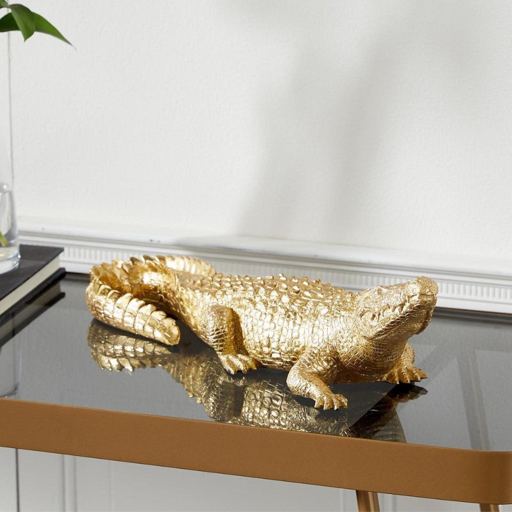 Golden crocodile sculpture on a glossy table.