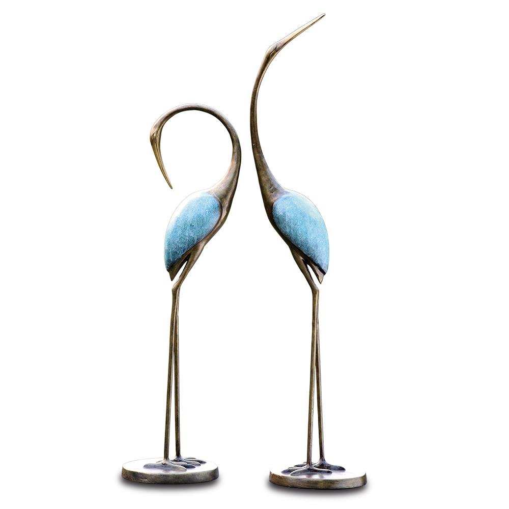 Two elegant bird sculptures with blue bodies and long legs.