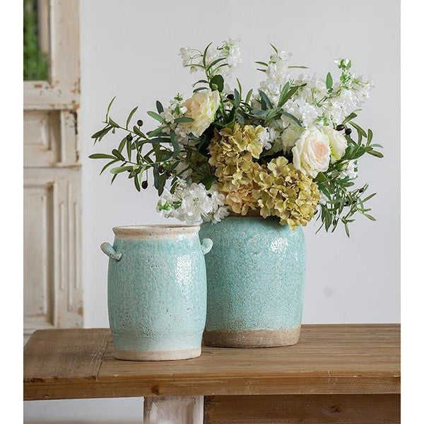 Ceramic vases with floral arrangement on a wooden table.
