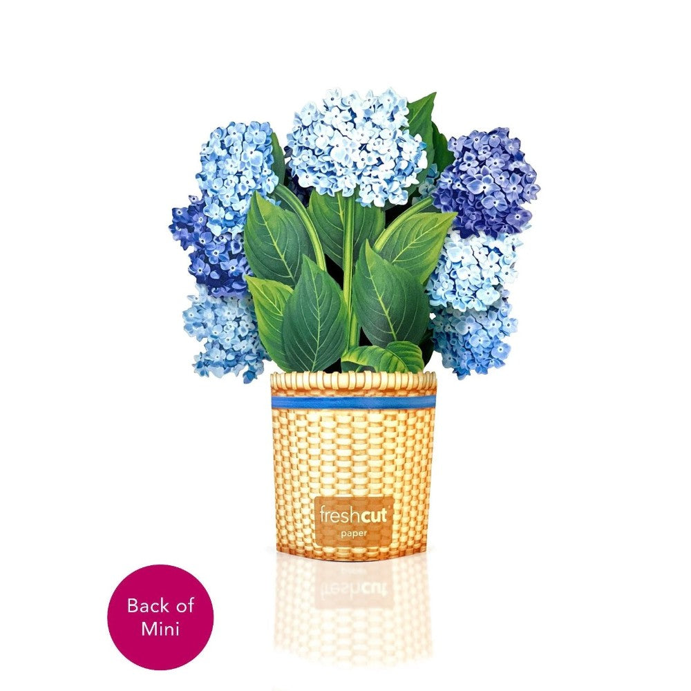 Paper hydrangeas in a basket with green leaves.