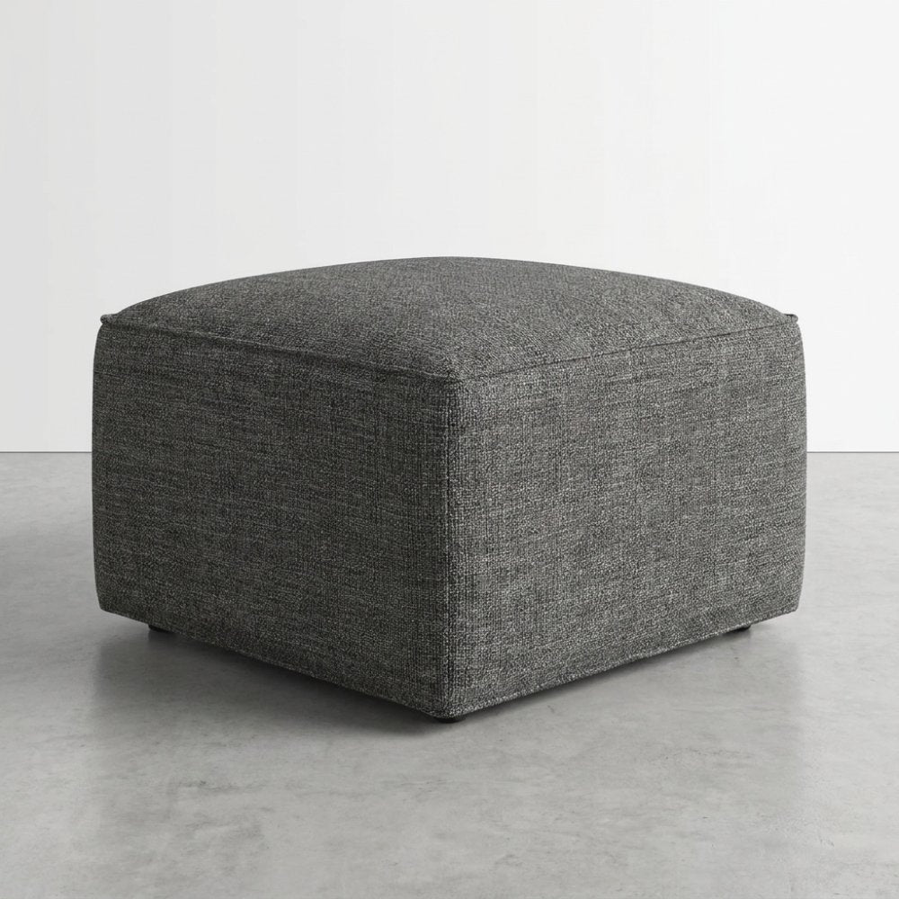 Gray square ottoman on a concrete floor.