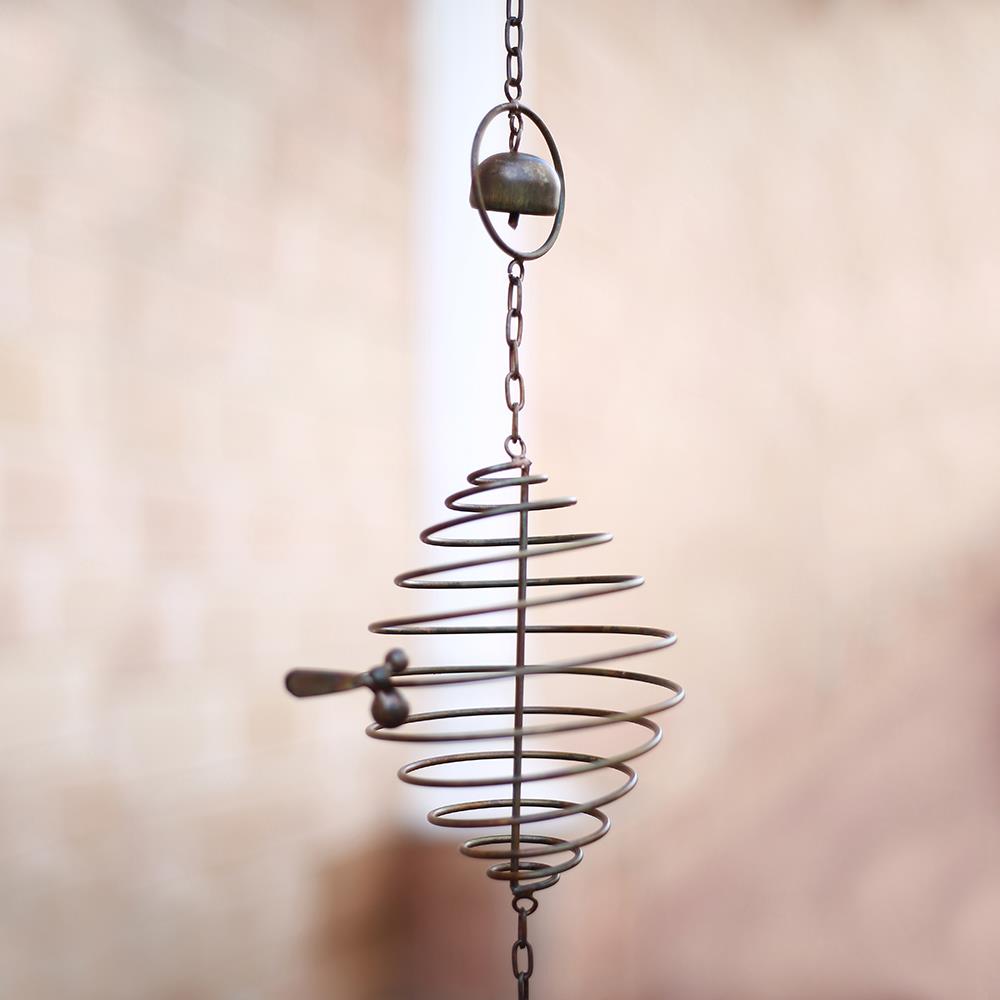 Hanging spiral wind chime with a bell on a chain.