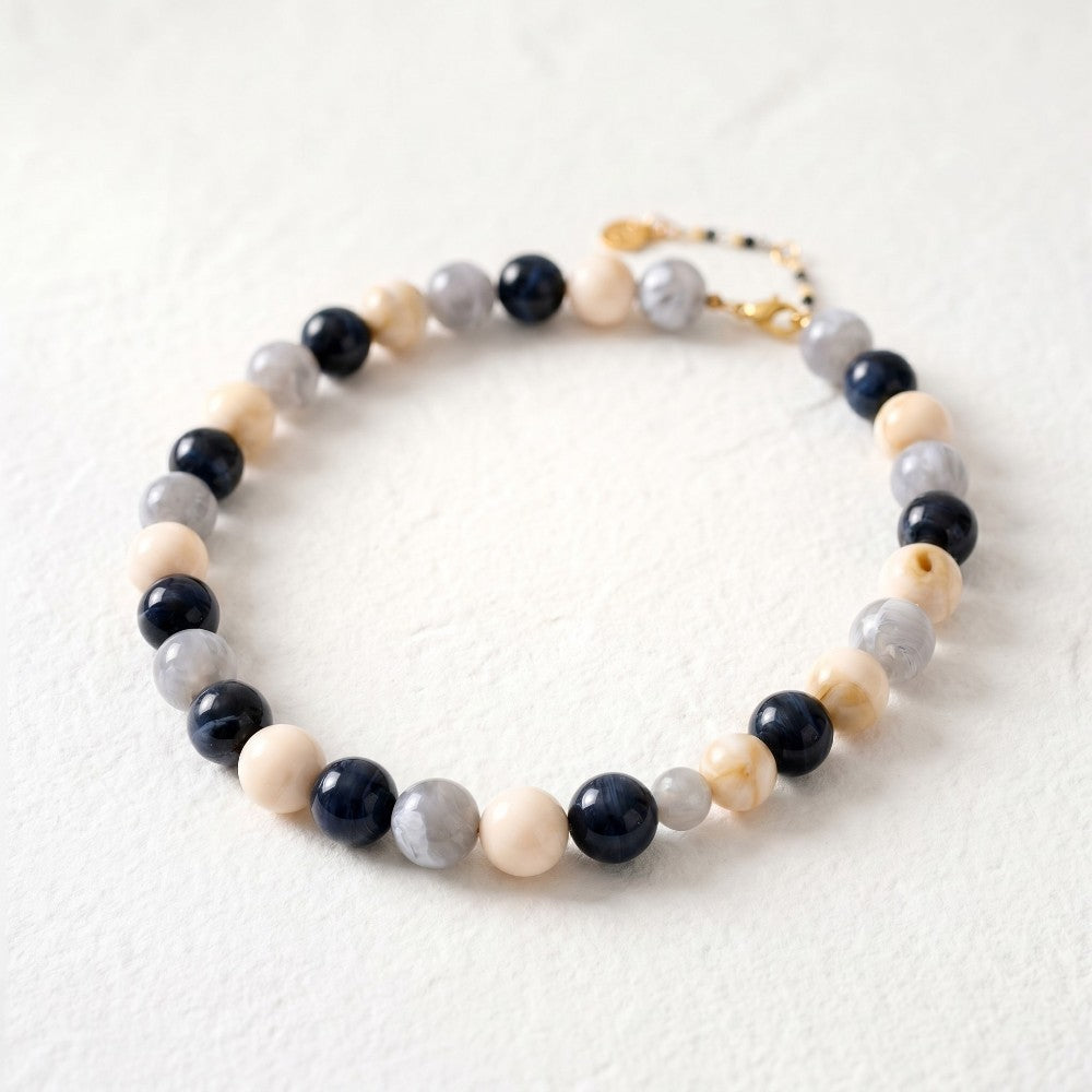 Beaded bracelet with blue, gray, and beige stones on a light background.