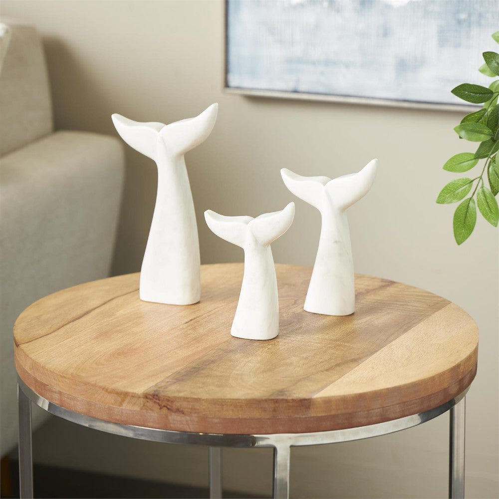 Three white whale-tail sculptures on a round wooden table.