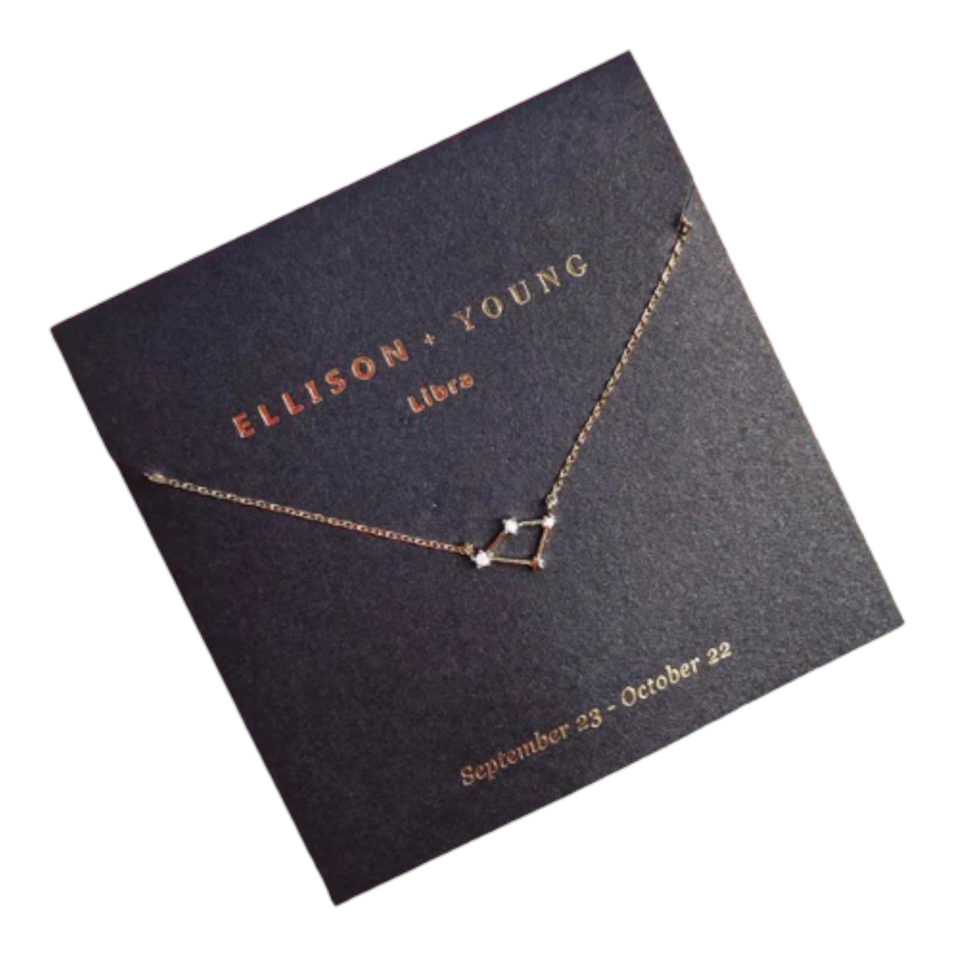 Gold Libra constellation necklace on black card.