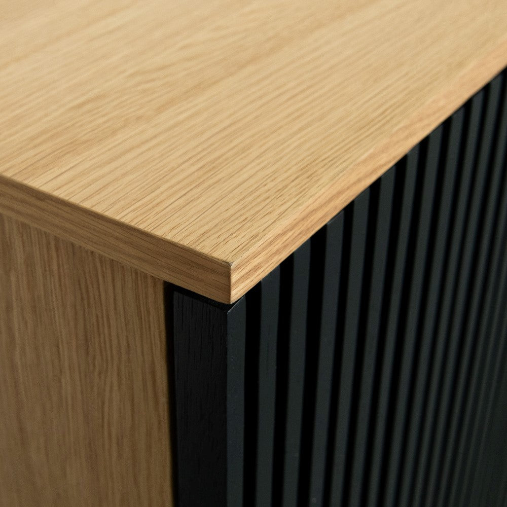 Wooden cabinet corner with black slatted side.