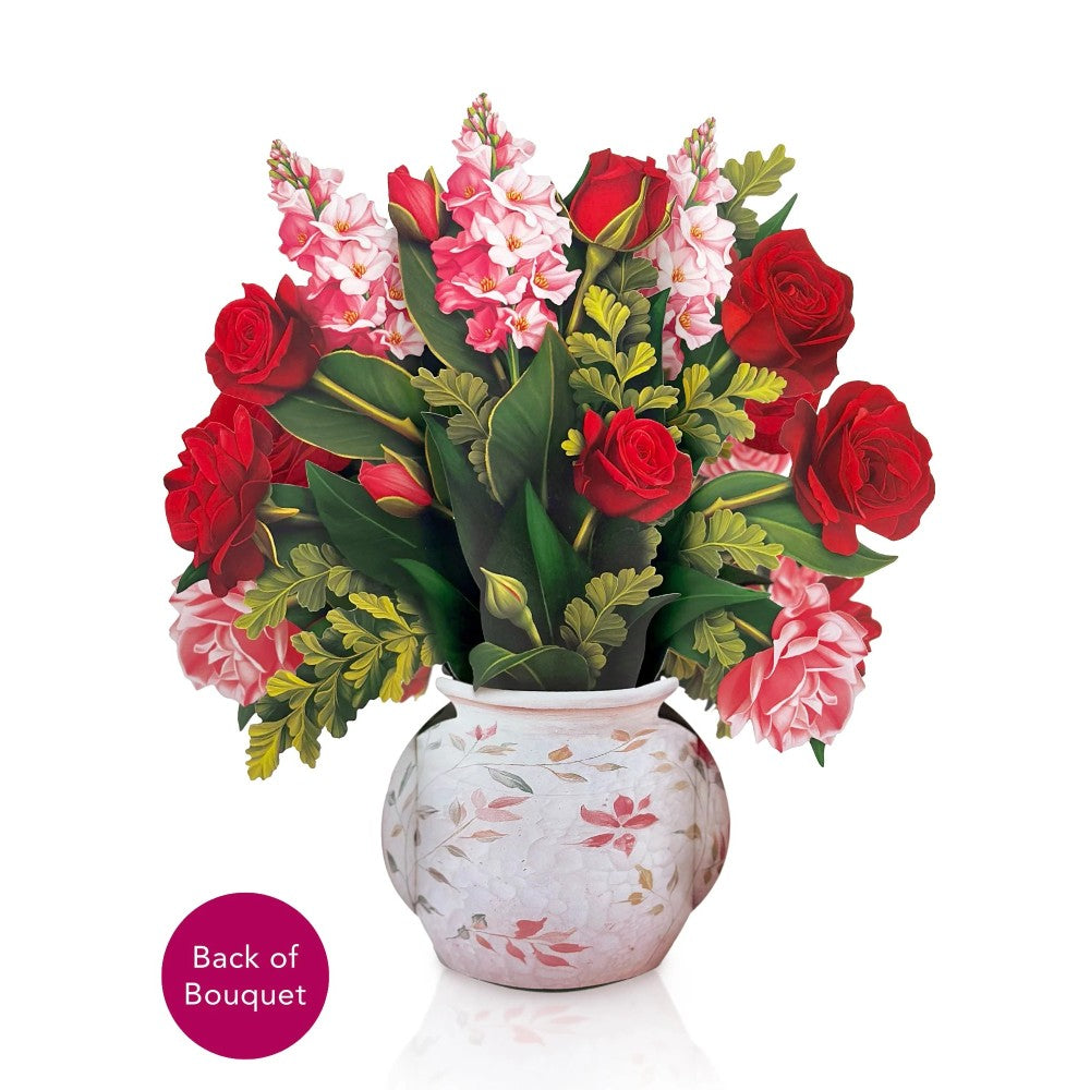 Bouquet of red roses and pink blooms in a floral vase.
