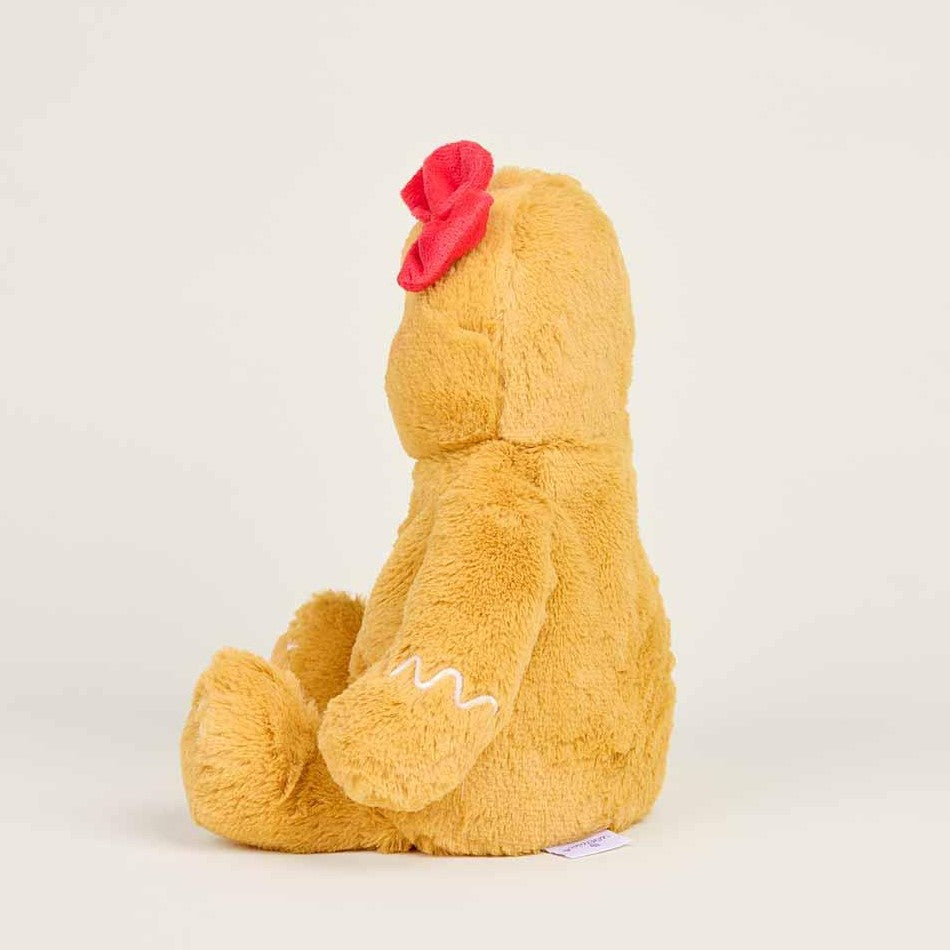 Side view of a brown teddy bear with a red bow, sitting upright.