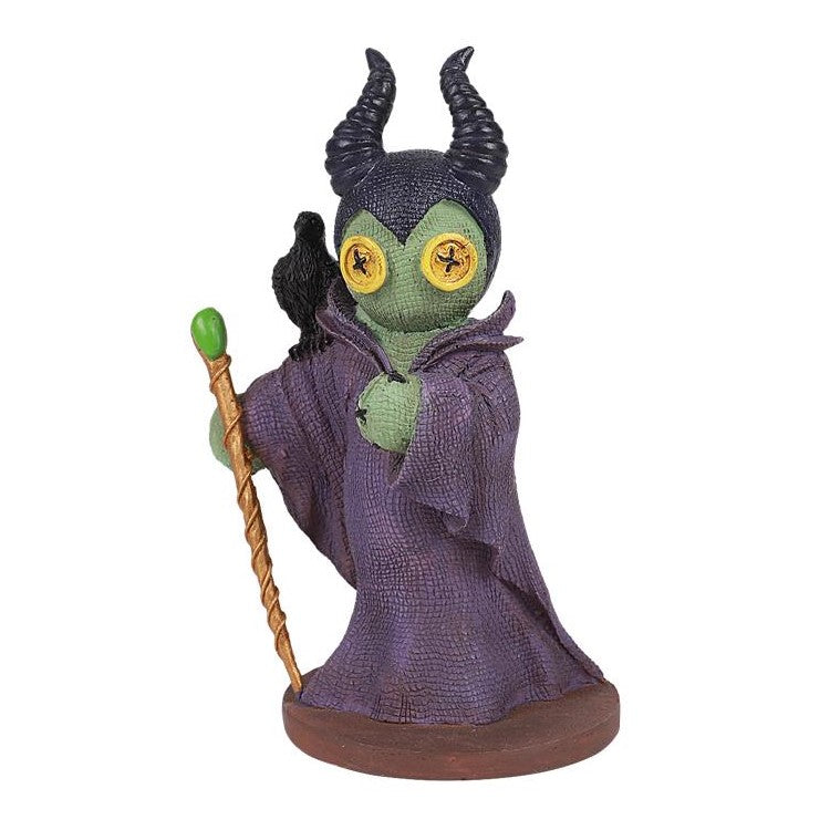 Figure with horns and button eyes, holding a staff, in a purple cloak.