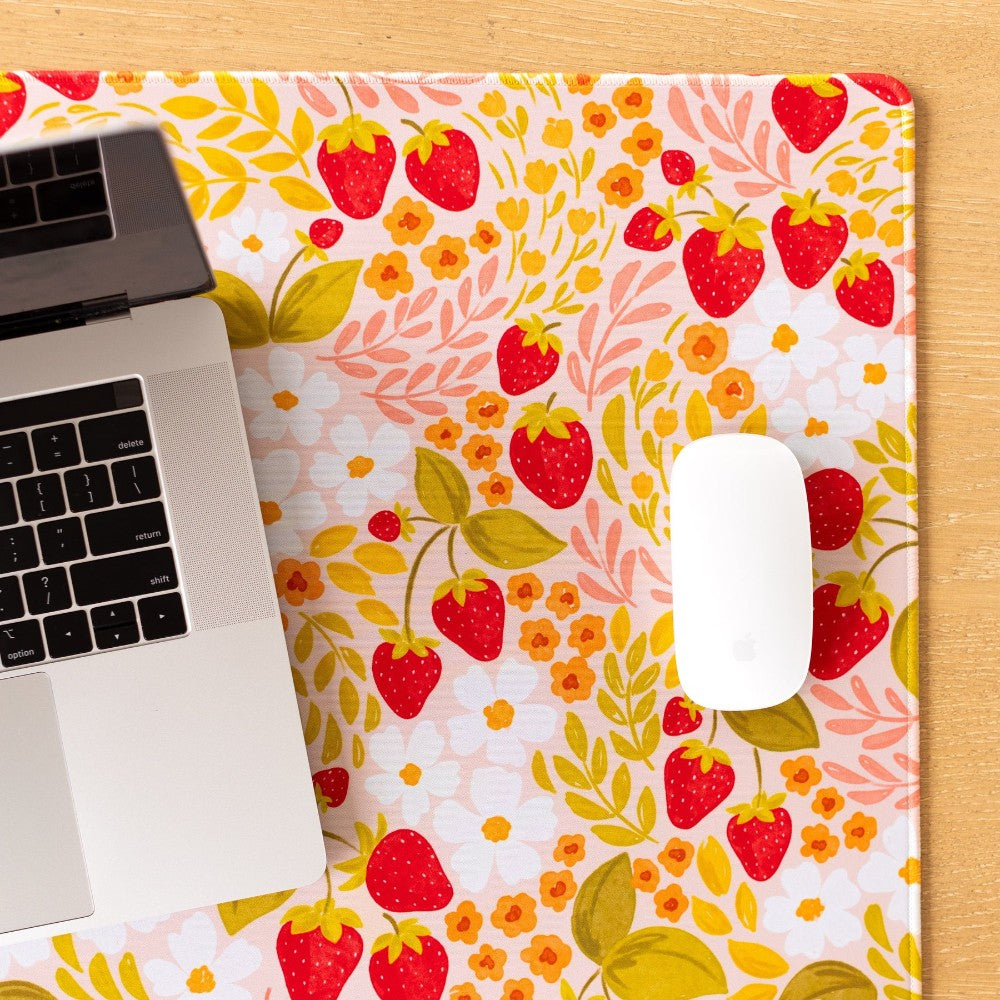 Laptop and mouse on a strawberry-themed mat.