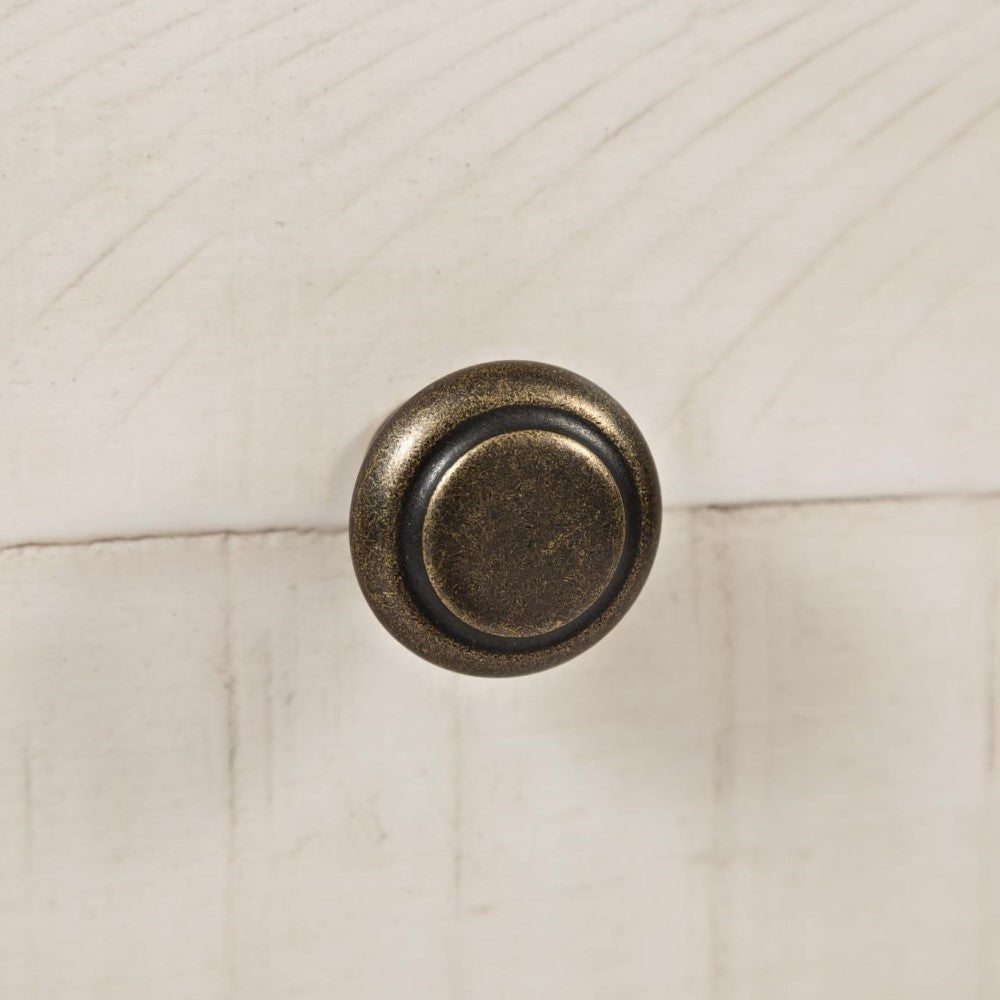 Round bronze knob on textured wood surface.