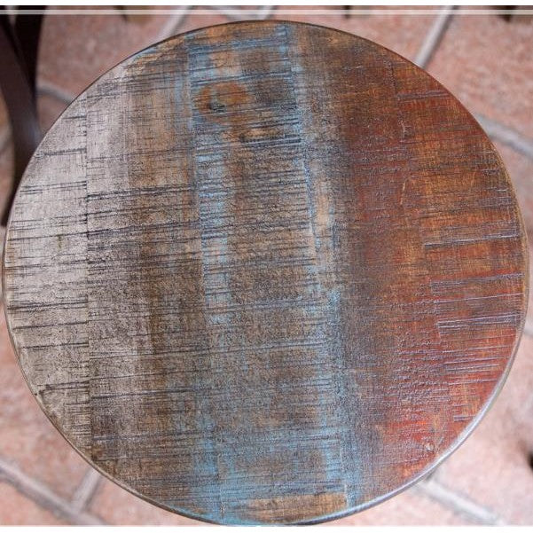 Round wooden table with a distressed, multicolored finish.