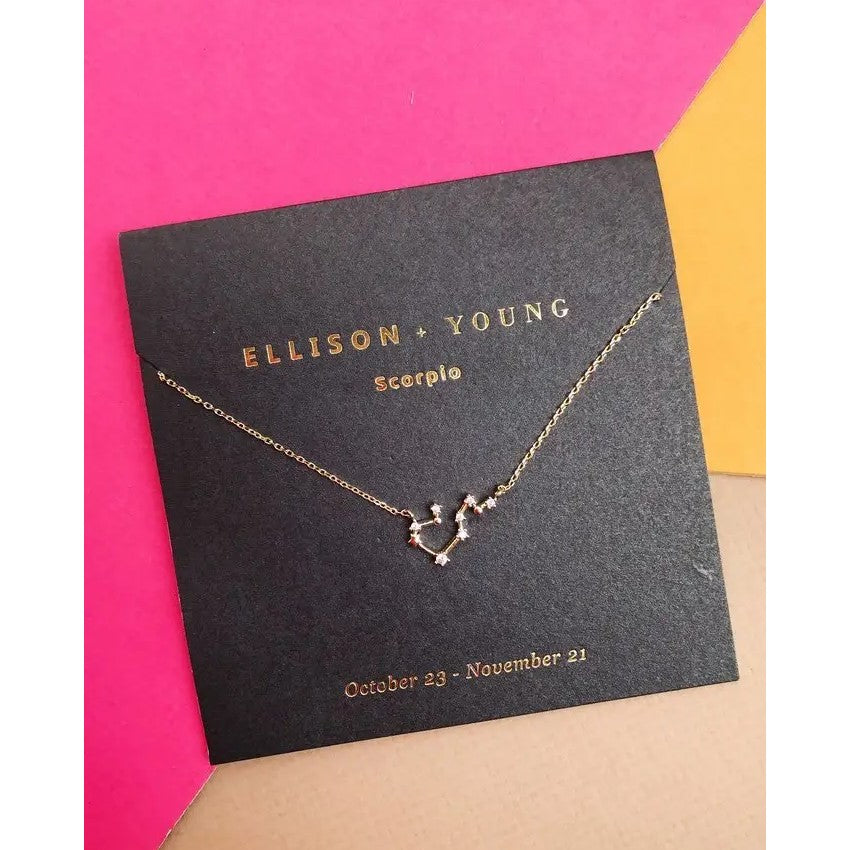 Gold Scorpio necklace on black card with pink and yellow background.