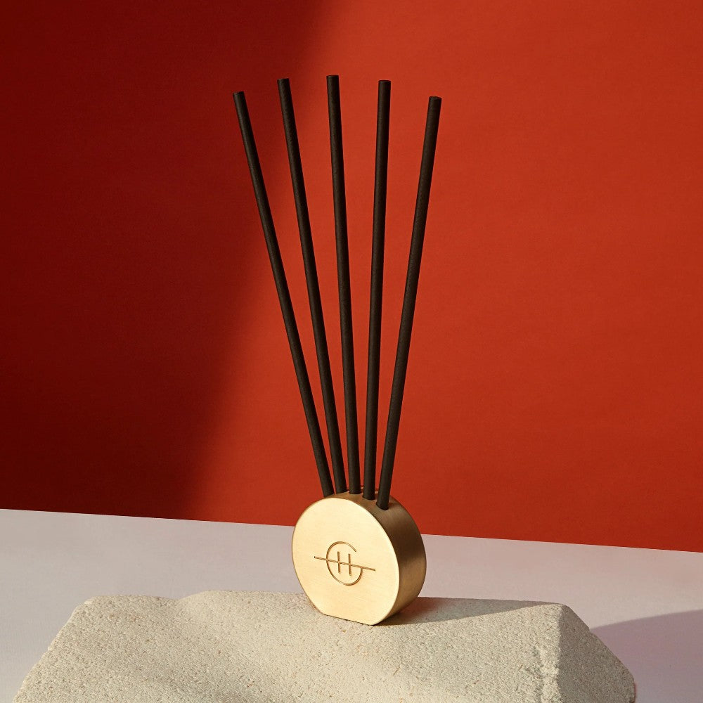 Decorative incense sticks in a gold holder, red background.