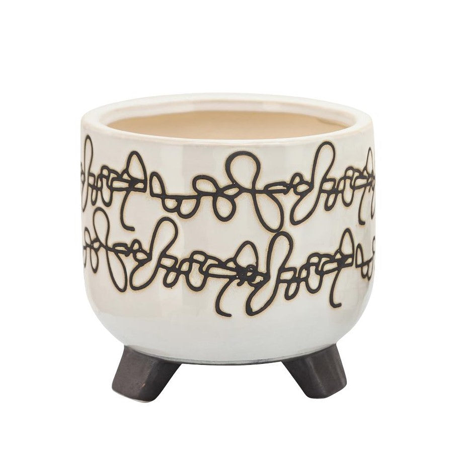 White ceramic planter with abstract black line design and tripod legs.