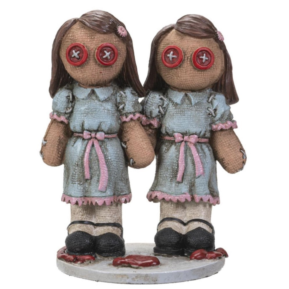 Two button-eyed dolls in blue dresses, standing together.