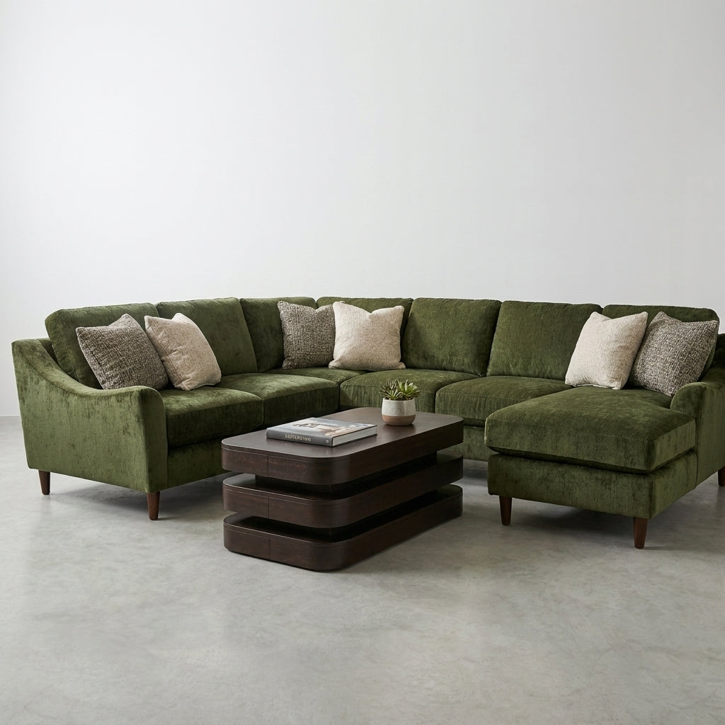 Green sectional sofa with pillows and a modern coffee table on a clean, light floor.