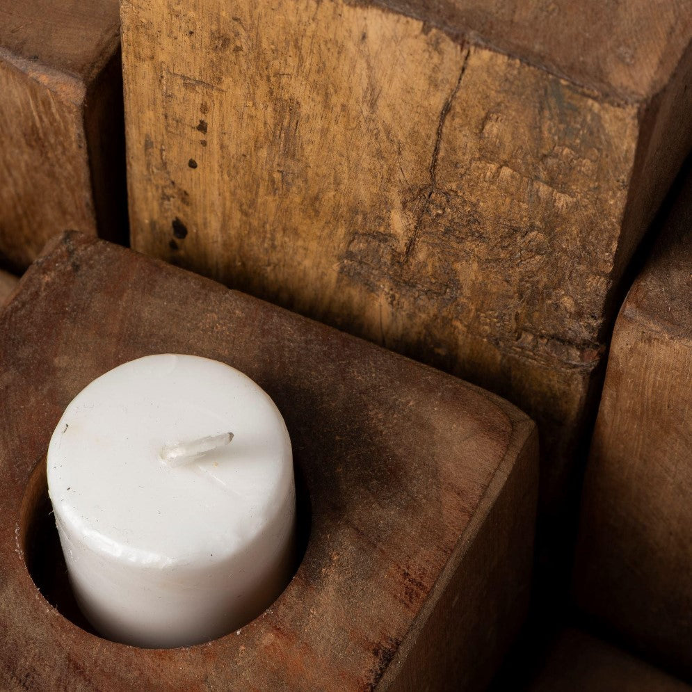 White candle nestled in a rustic wooden holder.