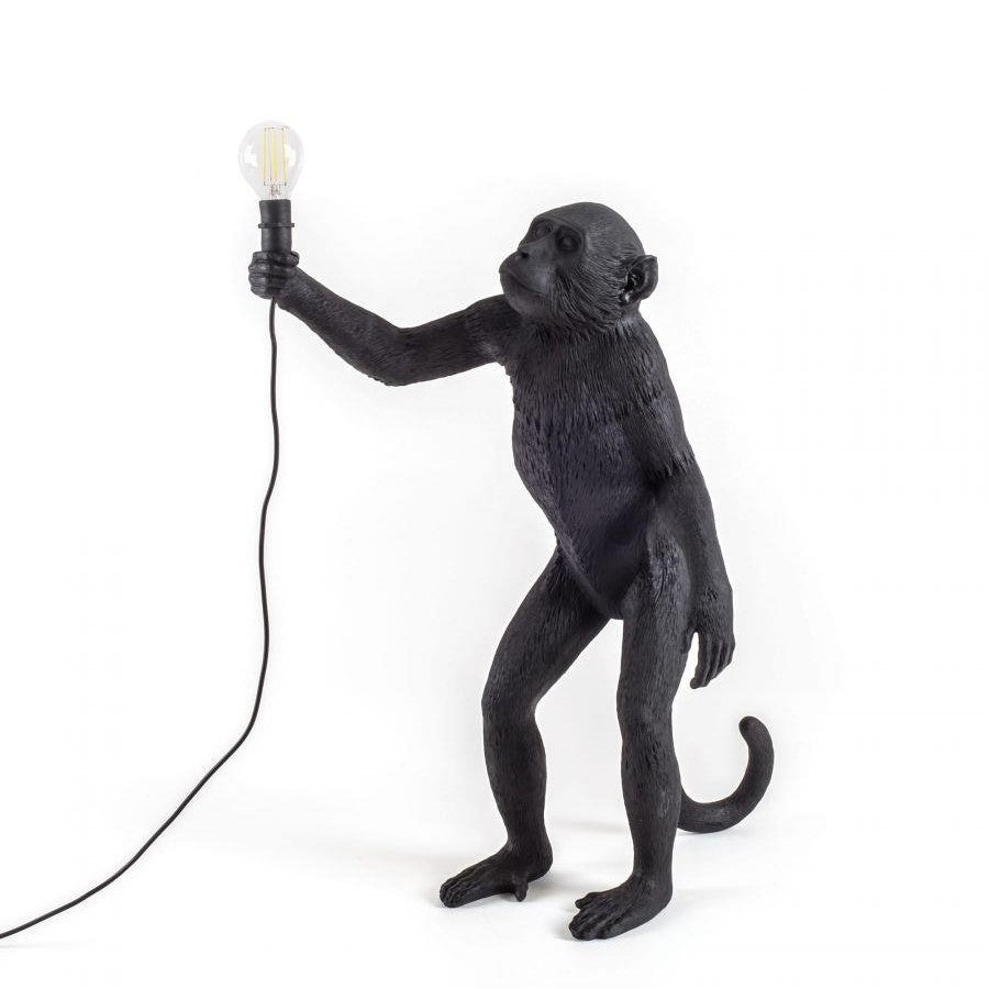 Black monkey lamp holding a light bulb.