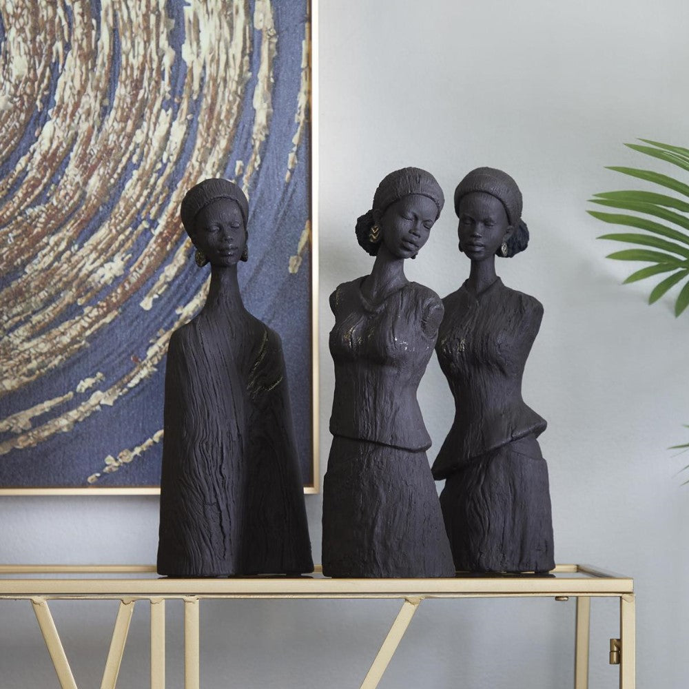 Three black statues on a table, abstract art in the background.