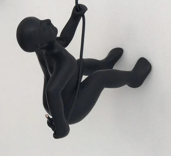 Black wall art of a figure climbing with a rope.