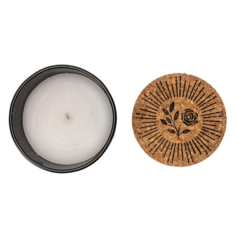 White candle in a black tin with floral cork lid.