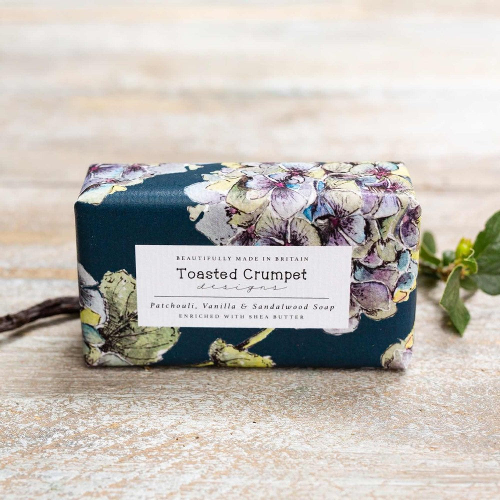 Floral-designed soap bar with "Toasted Crumpet" label on rustic surface.