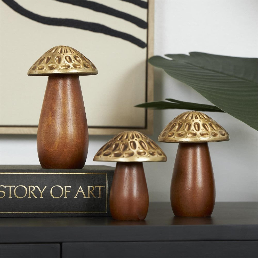 Wooden and brass mushroom decor on an "Art" book with a plant nearby.