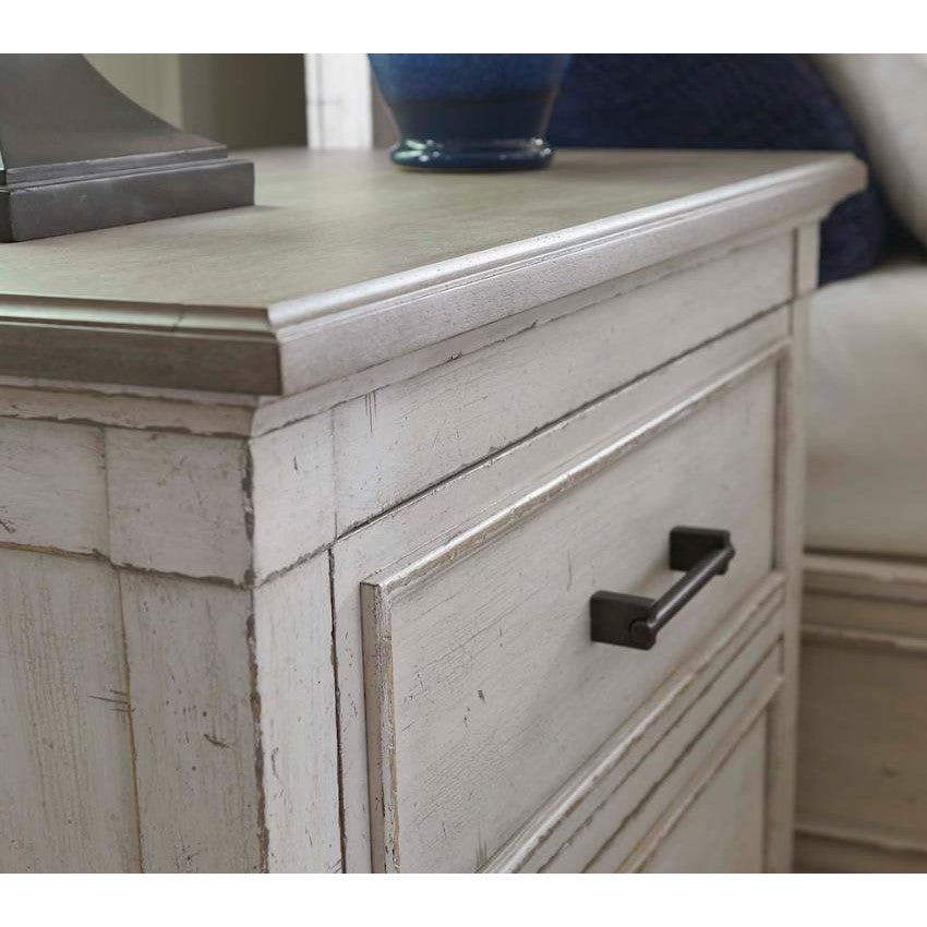Rustic white wood cabinet with black handles and a blue vase.