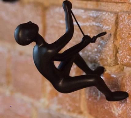 Black climbing sculpture on a brick wall.