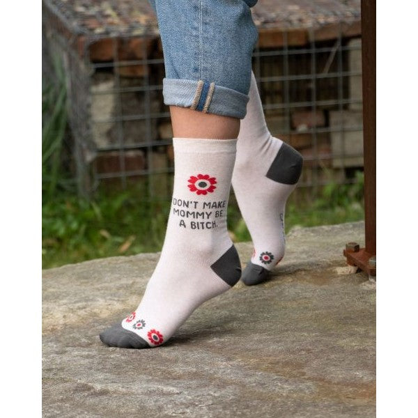 Person wearing humorous socks with floral design and rolled jeans.