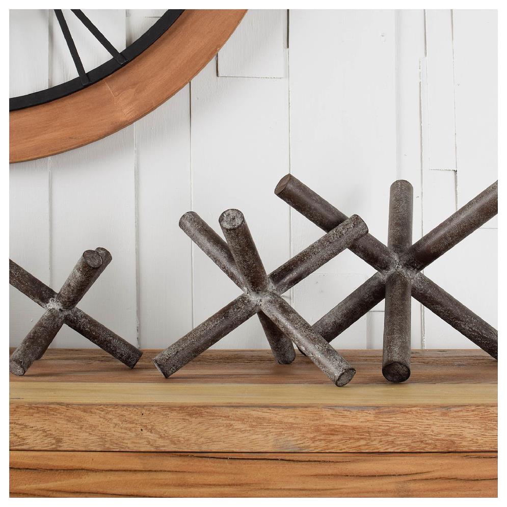 Metal jack sculptures on a wooden shelf, set against a rustic wall.