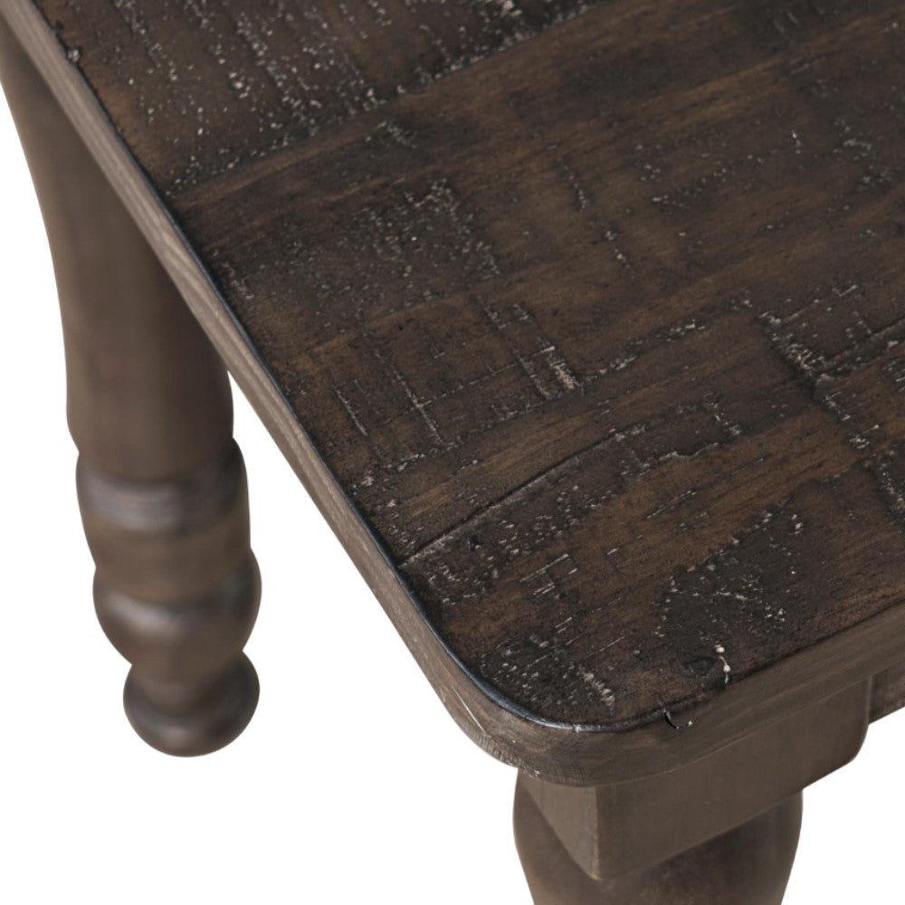 Dark wooden table corner with a textured surface and turned legs.
