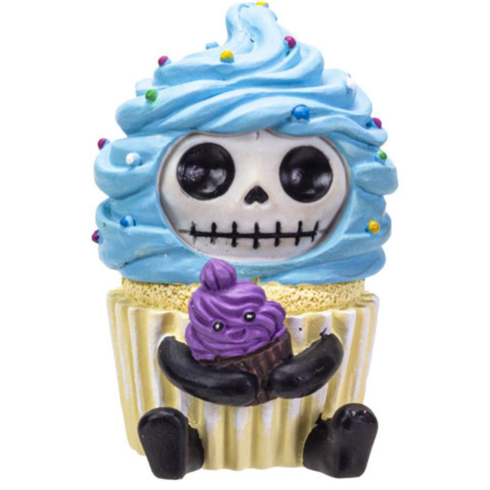 Cupcake with a skull face, blue frosting, and holding a mini purple cupcake.