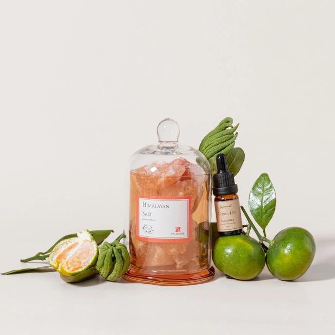 Himalayan salt, citrus fruits, and essential oil bottle arrangement.