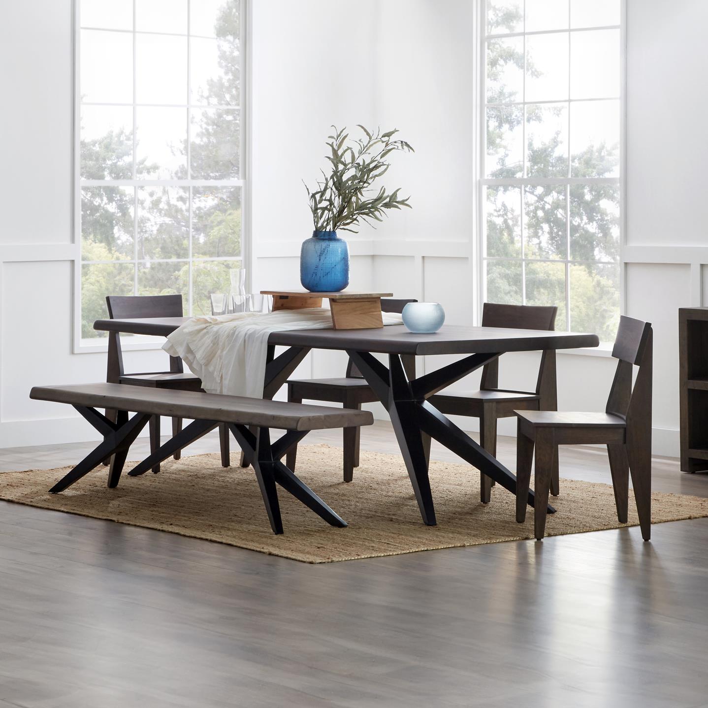 Modern dining table with chairs, bench, and blue vase in bright room.